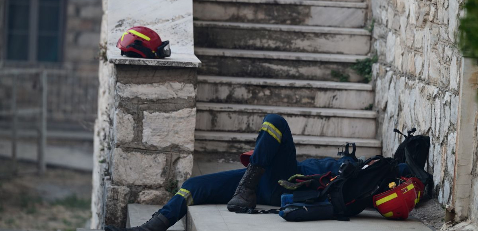 Φωτιά στην Αττική: Συγκλονιστική φωτογραφία - Αποκαμωμένος πυροσβέστης ξεκουράζεται σε πεζούλι